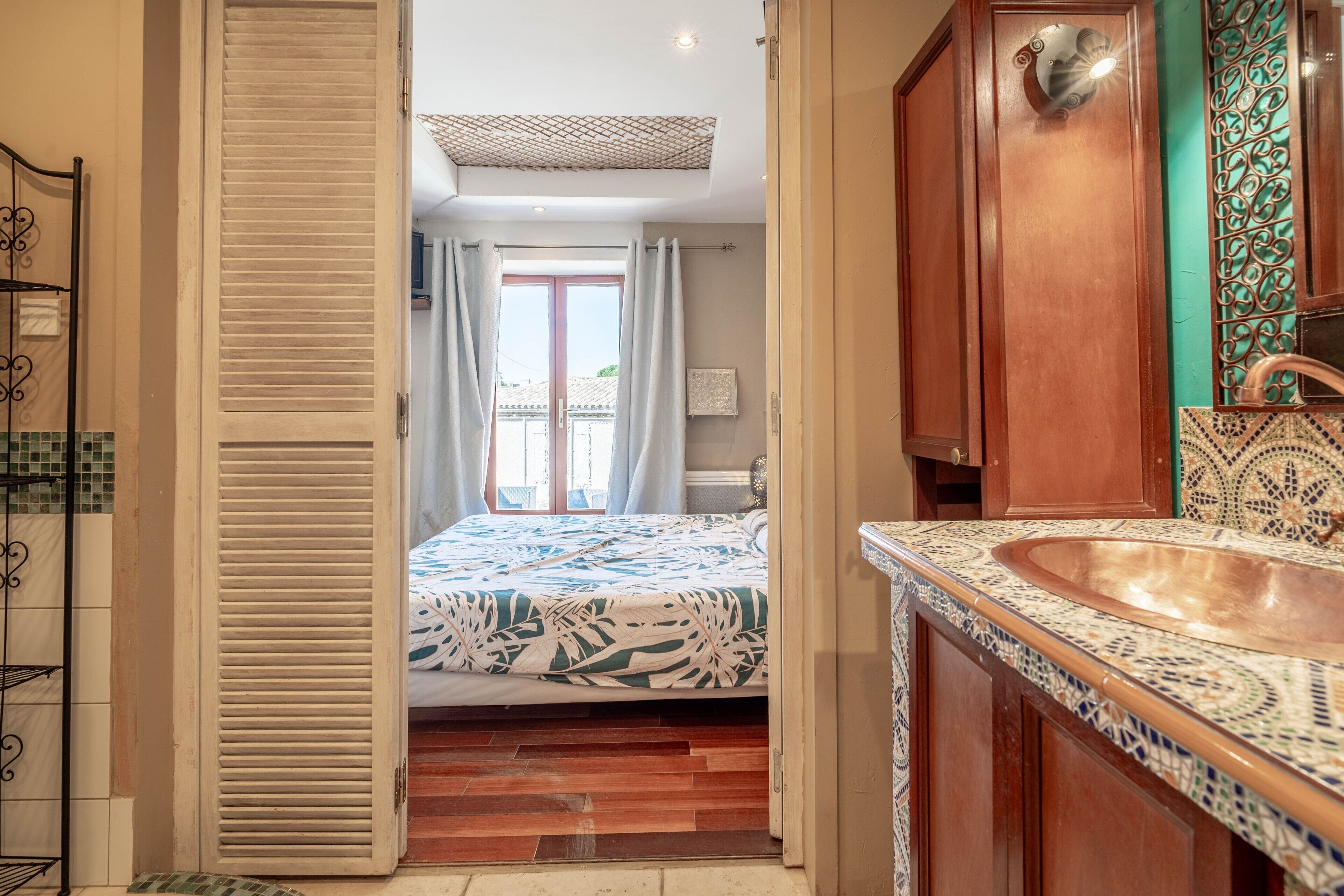 A bathroom with a sink, mirror, and patterned tiles.