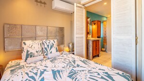 Ein Schlafzimmer mit Bett, Kopfstütze, Nachttisch und angrenzendem Badezimmer.