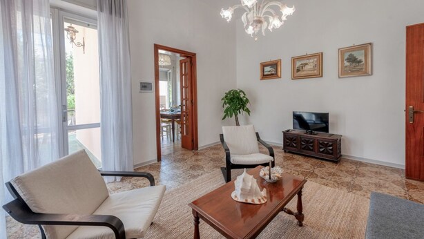 Una sala de estar con sofá, sillón, mesa de centro, televisor y objetos decorativos.