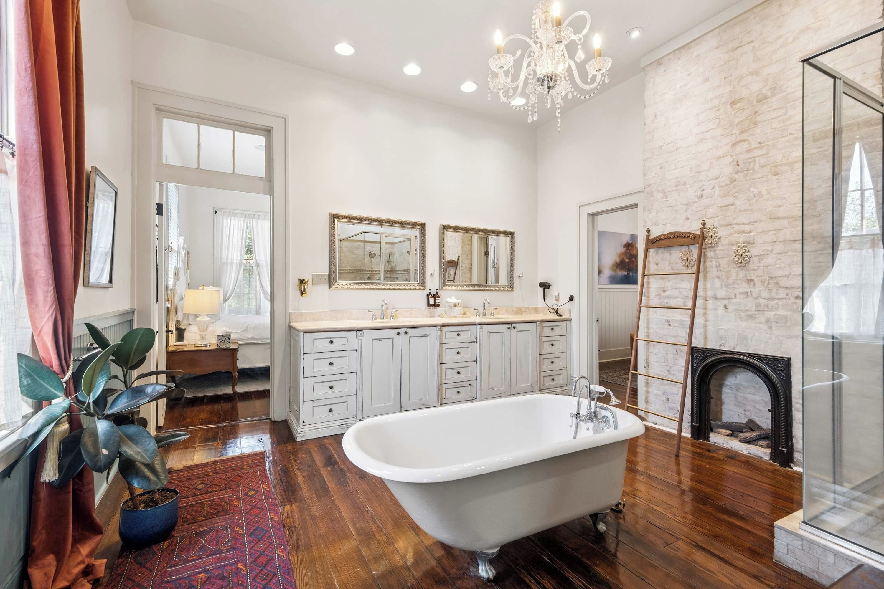 A spacious bathroom with a freestanding bathtub, a large mirror, and a chandelier.