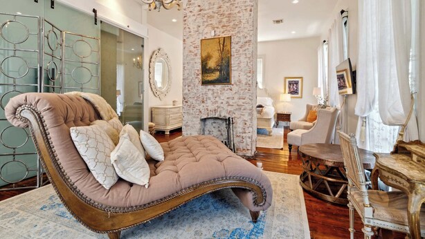 A luxurious room with a large, cushioned chaise lounge, a fireplace, a dining area, and a view of the city. - Bright Villa w Heated Pool & Pool Table 5br 4ba (New Orleans)
