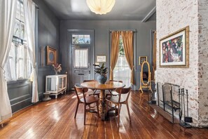 Un coin repas avec une table et des chaises en bois, un buffet blanc et un miroir.