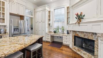 A spacious kitchen with white cabinetry, a granite countertop, and a built-in fireplace.