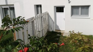 Un bâtiment blanc avec une entrée fermée par un portail, une petite porte et des fenêtres.
