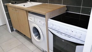 Une petite cuisine équipée d’un lave-linge, d’un évier et d’une cuisinière.