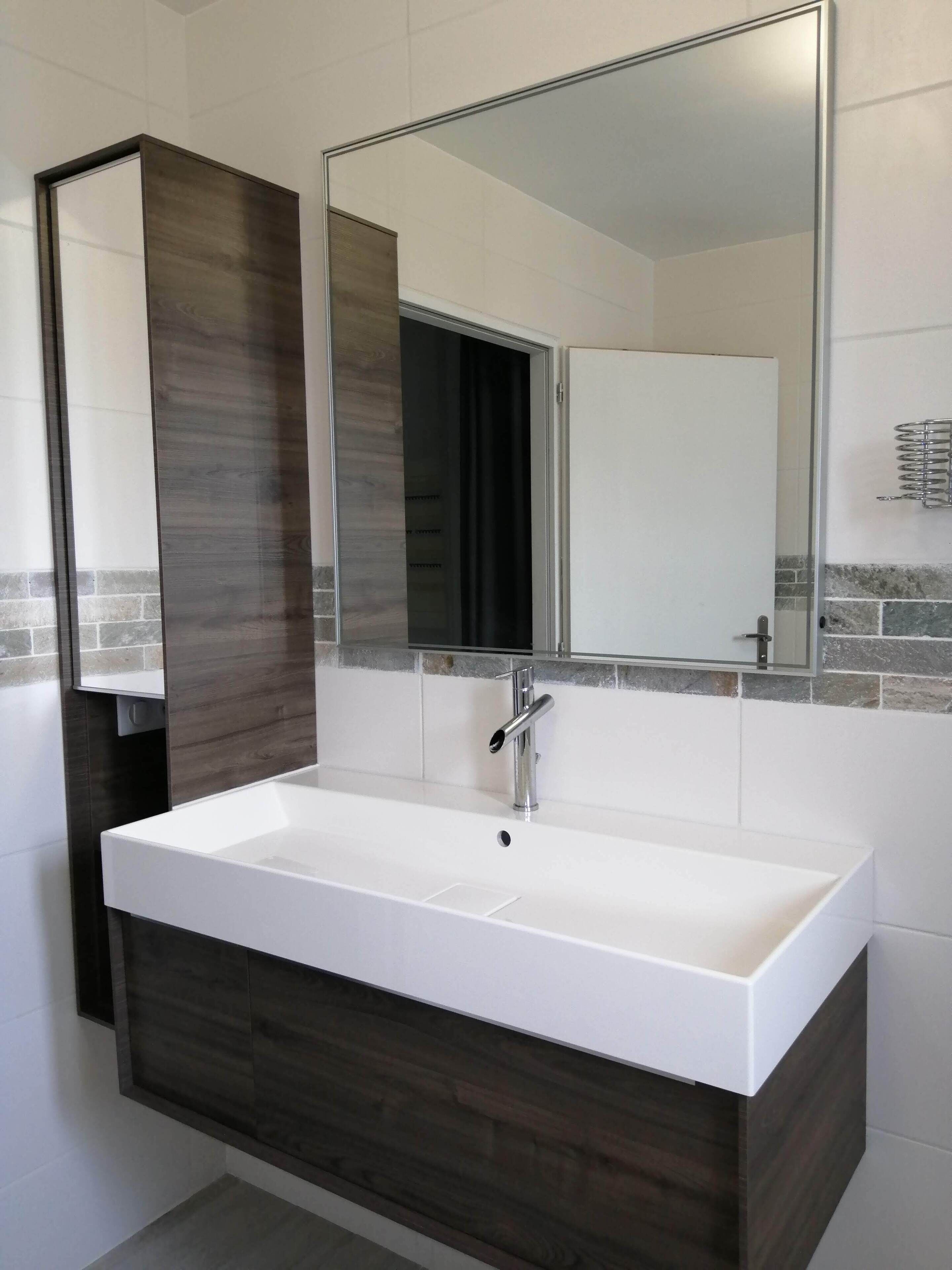 A modern bathroom with a large rectangular sink, a mirror above it, and a dark wood vanity.
