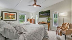 A bedroom with a bed, a desk, a chair, a ceiling fan, and two windows. - Sunny 3BR w/ Firepit + Game Yard | Walk to Green Lake (Interlochen)