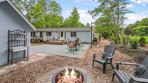 A residential property with a patio area, outdoor seating, and a fire pit. - Sunny 3BR w/ Firepit + Game Yard | Walk to Green Lake (Interlochen)
