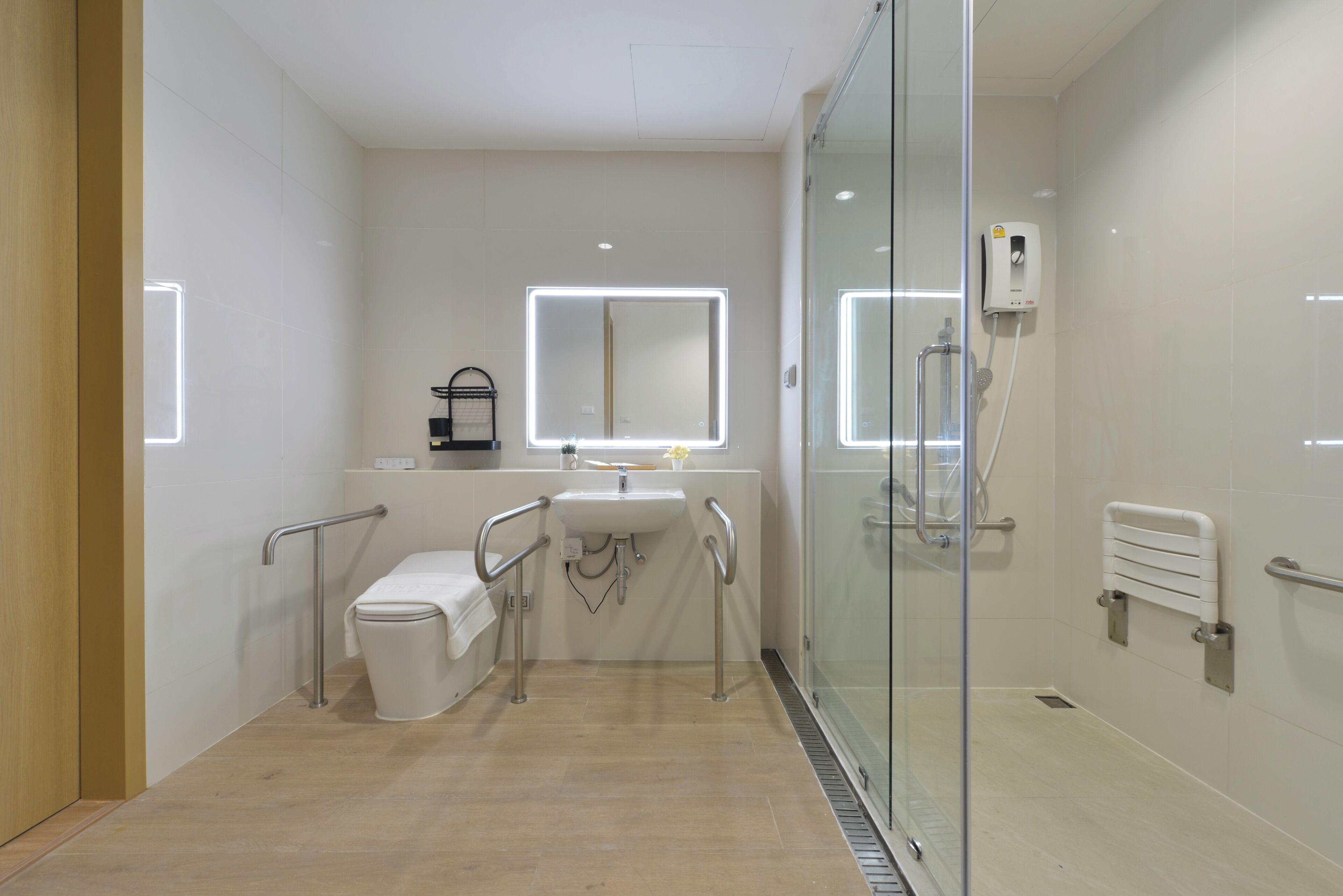 Et moderne badeværelse med toilet, håndvask og glas brusekabine.