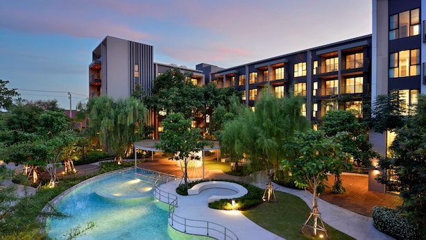 Un hotel moderno con piscina, immerso nel verde e dotato di vialetti illuminati.