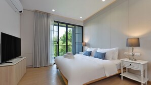 Una camera d'albergo moderna con un letto grande, una TV a schermo piatto, un comodino e una finestra con tende.
