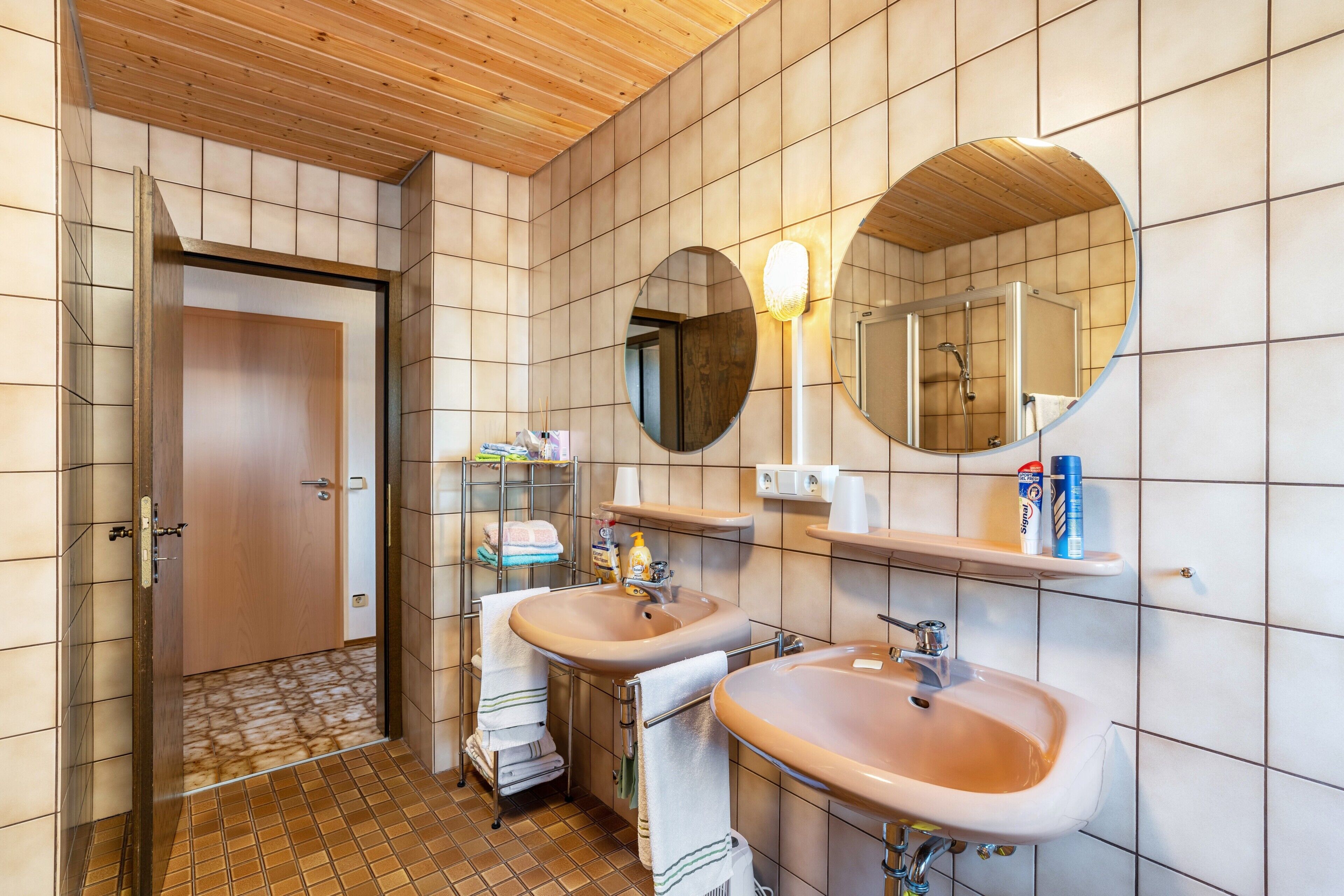 A bathroom with two sinks, a mirror, and a shower.