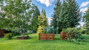 A grassy yard with wooden structures, trees, and a clear sky.