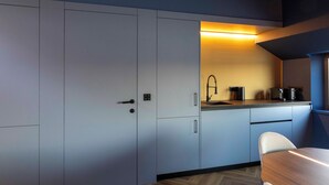 Una cocina moderna con gabinetes grises, una mesa de comedor de madera y una estufa empotrada.