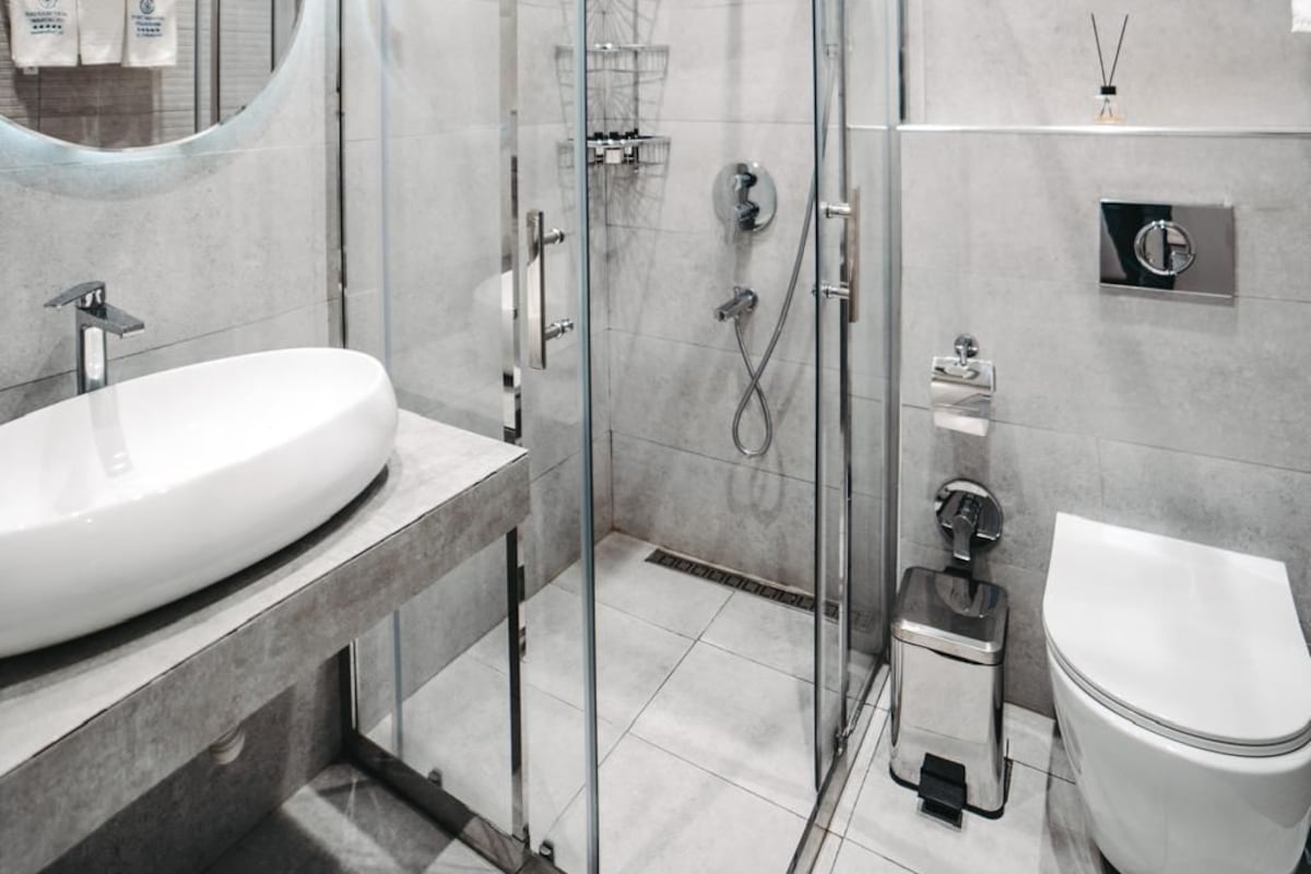 A modern bathroom with a glass-enclosed shower, a white sink, and a toilet.