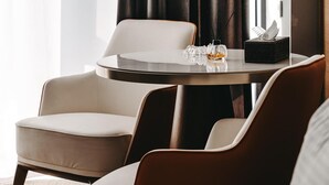 A modern hotel room with a round table, two chairs, a small decorative item, and a door. - Port Marine Hotel By HOLLYWOOD (Baku)