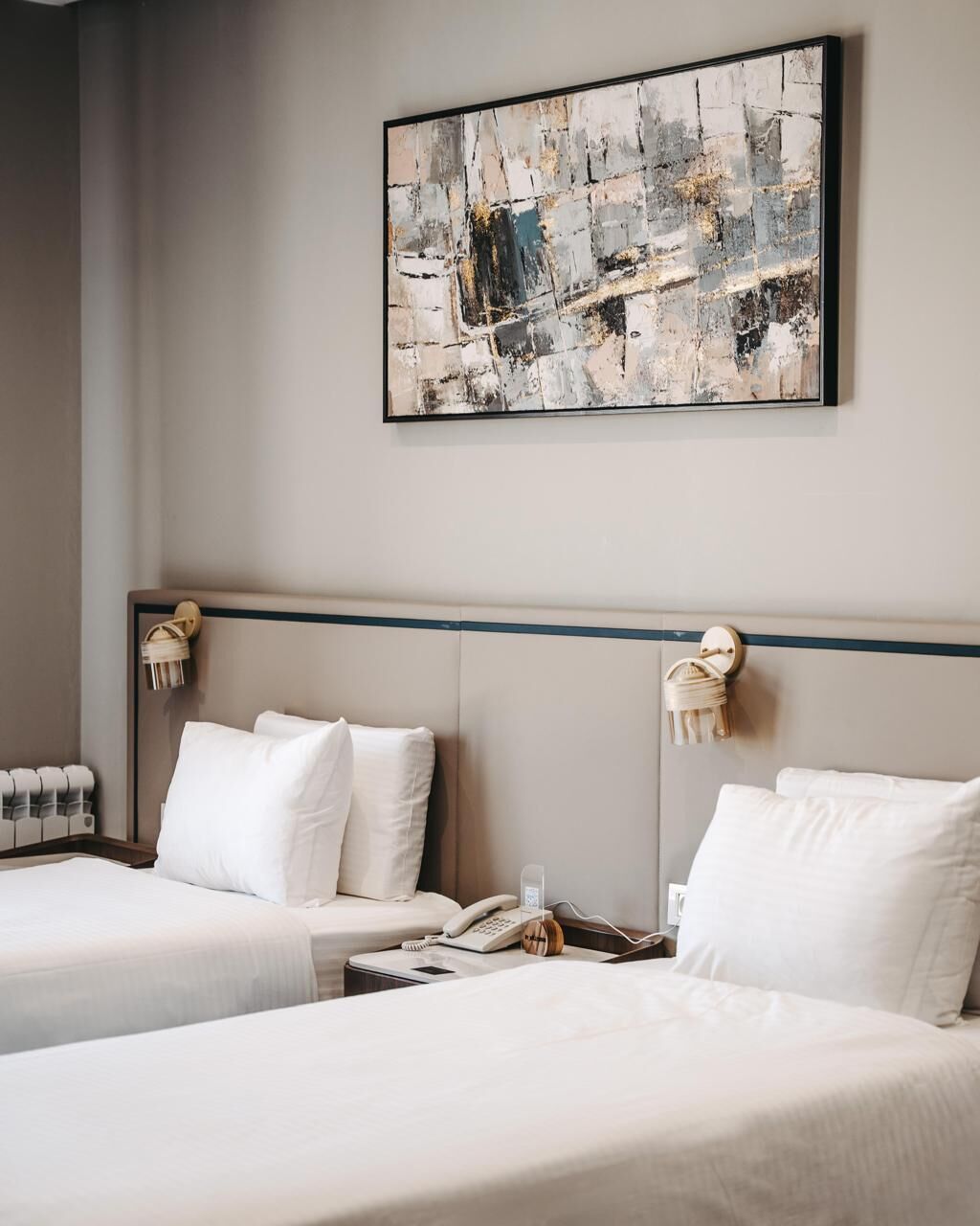 Habitación de hotel con dos camas, un cuadro abstracto grande y un teléfono en la mesita de noche.