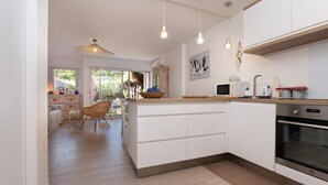 A modern kitchen with white cabinetry, a built-in oven, and pendant lighting.