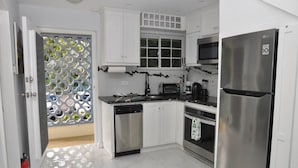 Een moderne keuken met witte kastjes, roestvrijstalen apparatuur en een glazen deur met een decoratief patroon.