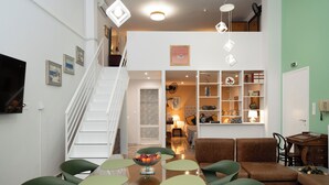 A dining area with a table, chairs, and a fruit bowl. There is a staircase leading to an upper level.