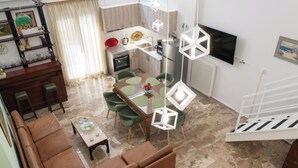 A modern living room with a dining area, a sofa set, a TV, and a staircase.