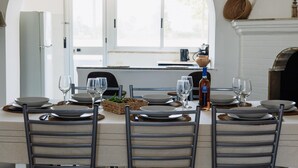 Comedor con una mesa preparada para cuatro, una chimenea y vistas a la cocina a través de un ventanal de arco.