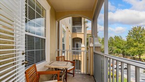 A balcony with a table and chairs, a view of a building, and a metal railing. - Relaxing 3BR retreat w/ balcony (Kissimmee)