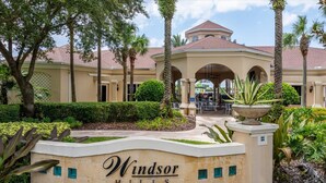 A sign for Windsor Hills Clubhouse with a covered patio area and palm trees. - Relaxing 3BR retreat w/ balcony (Kissimmee)