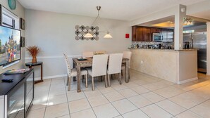 A modern kitchen with a central island, stainless steel appliances, and a dining area with a wooden table and chairs. - 2BR family retreat w/ resort access (Kissimmee)