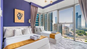 A modern hotel room with two beds, a large window with a city view, and a unique artwork on the wall.