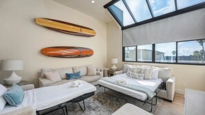 A modern hotel room with a large skylight, two beds, a sofa, and a coffee table.