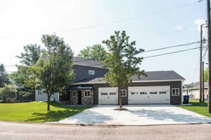 A two-story house with a garage, a front lawn, and two trees.