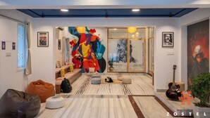 A modern interior with a colorful abstract mural, a glass door entrance, and a guitar on display. - Zostel Chennai Anna Nagar (Chennai)