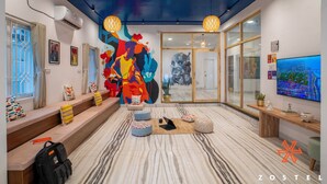A modern hotel lobby with a colorful abstract mural, a large TV screen, and a seating area with cushions. - Zostel Chennai Anna Nagar (Chennai)