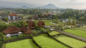 A rural village with traditional houses, rice paddies, and a mountain in the background. - Villa Aphrodite Ubud (Ubud)