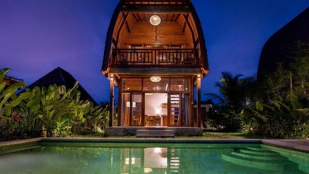 A wooden cabin with a balcony, a pool, and tropical vegetation. - Villa Aphrodite Ubud (Ubud)
