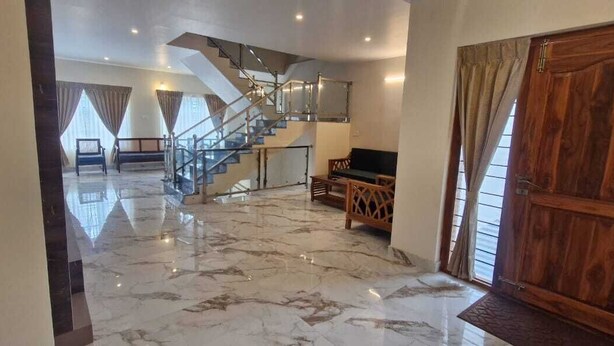 A spacious living area with a marble floor, a staircase, and a wooden door. - Darza delite (Ootacamund)