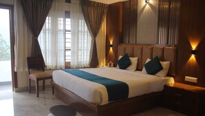 A large bed with a wooden headboard, two bedside tables, a chair, and a window with curtains. - Darza delite (Ootacamund)