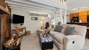 A living room with a high ceiling, a sofa, a coffee table, a TV, and a kitchen in the background. - Tanners Ridge 37  with Wintergreen Advantage (Wintergreen)