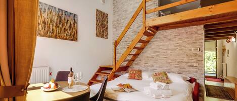 Un dormitorio con escalera tipo loft, un comedor con una mesa para dos personas y obras de arte en las paredes.