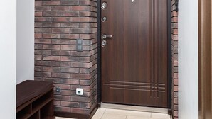 A wooden door with a brick accent wall, a coat rack, and a bench. - Stylish apartments near TSUM (Minsk)