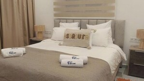 A hotel room with a bed, two bedside tables, a headboard, and a window with curtains. - Casadelmar (Essaouira)