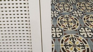 Een tegelontwerp met een rasterpatroon aan de linkerkant en een meer versierd, cirkelvormig ontwerp aan de rechterkant.