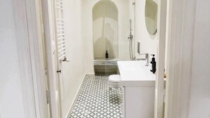 Een kleine badkamer met toilet, wastafel en douche.