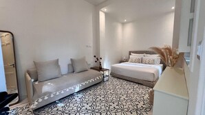 A modern bedroom with a sofa, a bed, and a patterned floor.