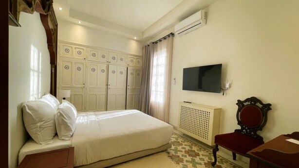 A bedroom with a bed, a TV, a radiator, and a wardrobe. - Chambre Rabaa   Dar Kbira (Tunis)