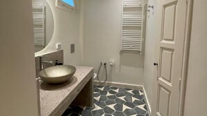 A bathroom with a large bowl sink, a mirror, a shower, and a door. - Chambre Rabaa   Dar Kbira (Tunis)
