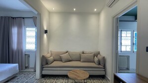 A modern living room with a sofa, a round coffee table, and a window with curtains.
