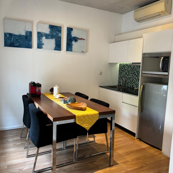 Una cocina moderna con una mesa de comedor, sillas y un refrigerador.