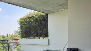 Una piscina en la azotea con mosaicos azules, una escalera metálica y vistas a zonas verdes y edificios al fondo.